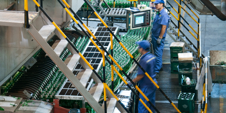 Workers operating a large machine within a food manufacturing plant.