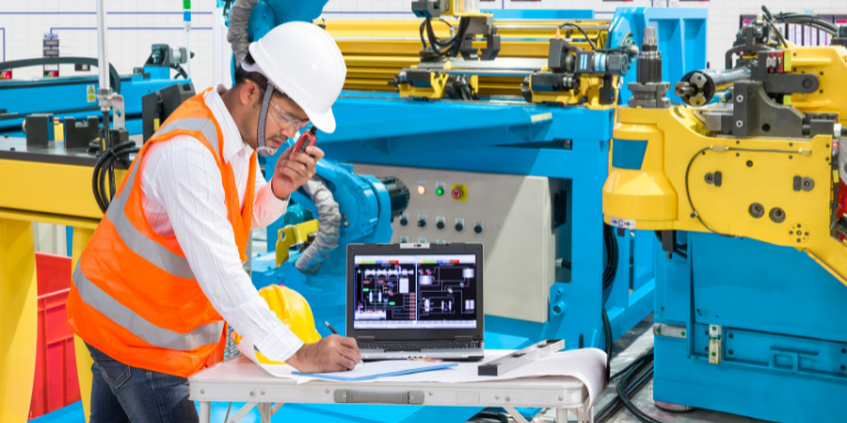 An equipment manufacturing employee operating a machine using a computer.