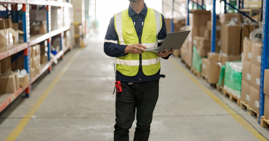 A plant manager doing a thorough inspection of operations on a laptop at a manufacturing plant.