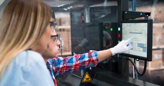 Two manufacturing plant employees operating a system using a tablet.