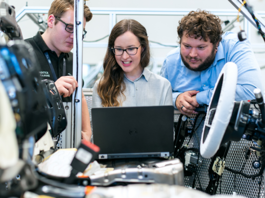 A group of automotive manufacturers at work on a computer.