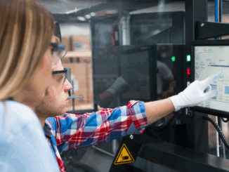 Two manufacturing plant employees operating a system using a tablet.
