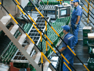 Workers operating a large machine within a food manufacturing plant.