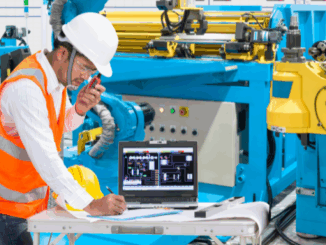 An equipment manufacturing employee operating a machine using a computer.