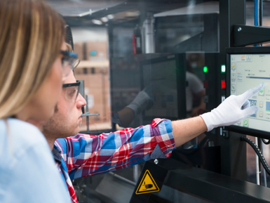 Two manufacturing plant employees operating a system using a tablet.